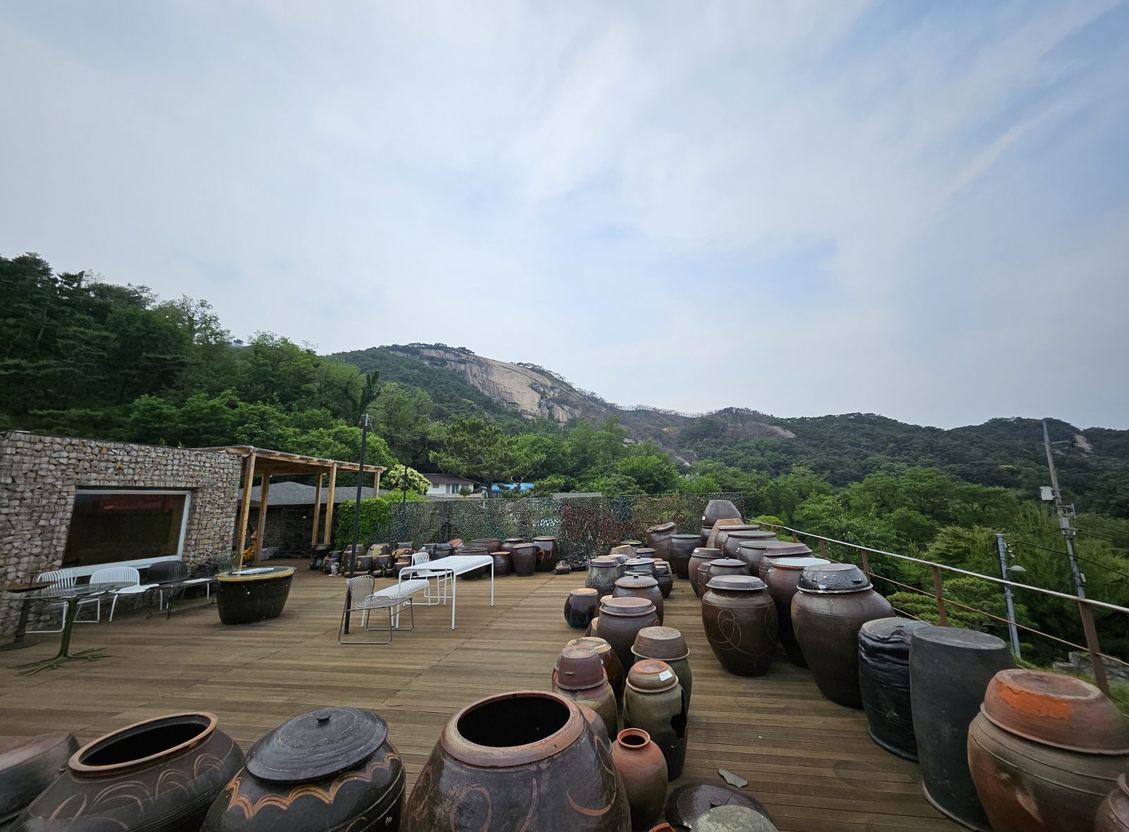 The rooftop deck of the Mokin Museum in Buam-dong, Seoul, covered in traditional onggi jars with the granite face of Inwangsan behind