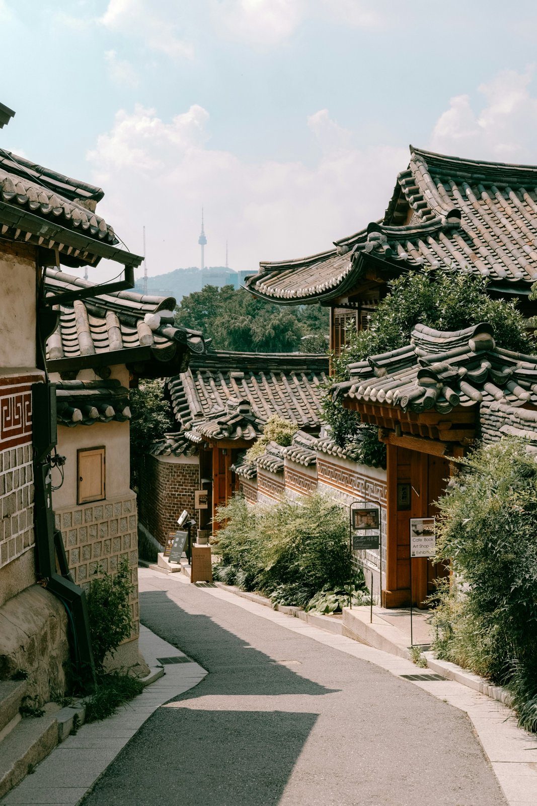 A quiet hanok street in Bukchon with curved tiled roofs and Namsan Tower