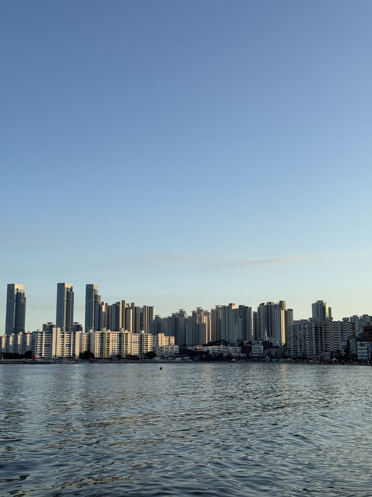 The Gwangalli waterfront skyline in Busan seen from the water, with high-rise towers behind the beach