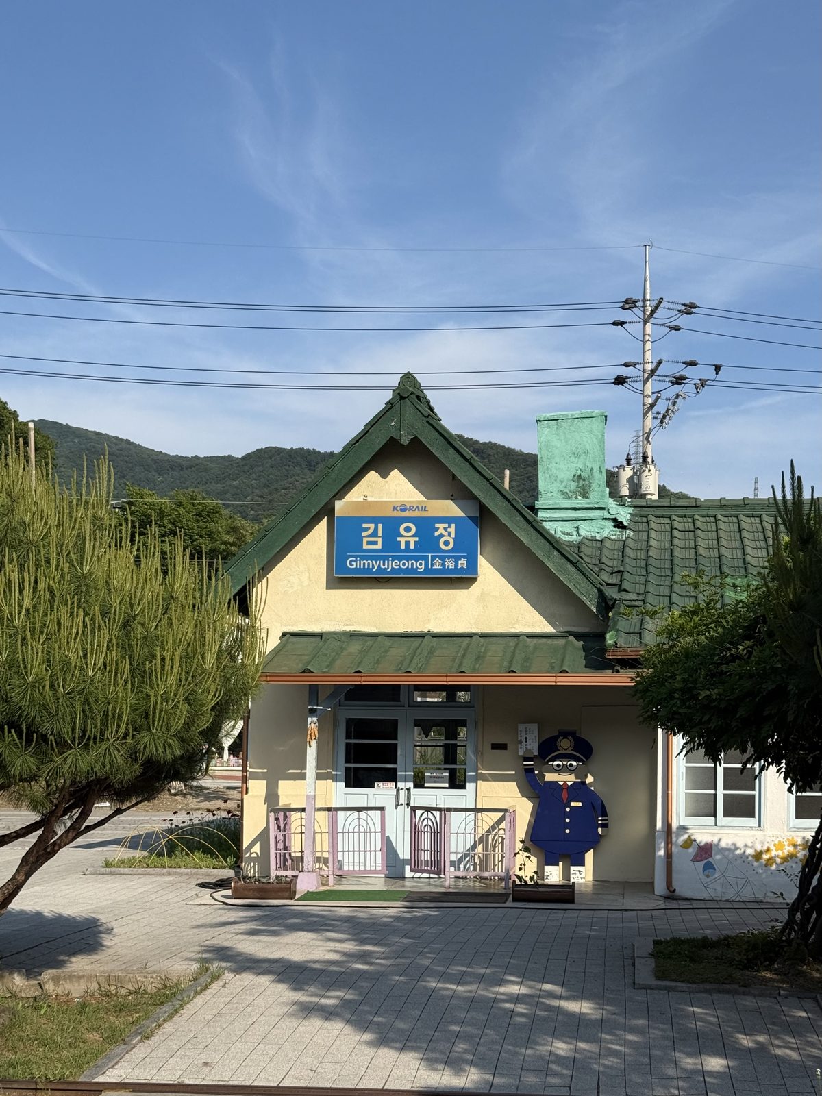 The old Gimyujeong Station building near Chuncheon, a small green-roofed station with a Korail nameplate