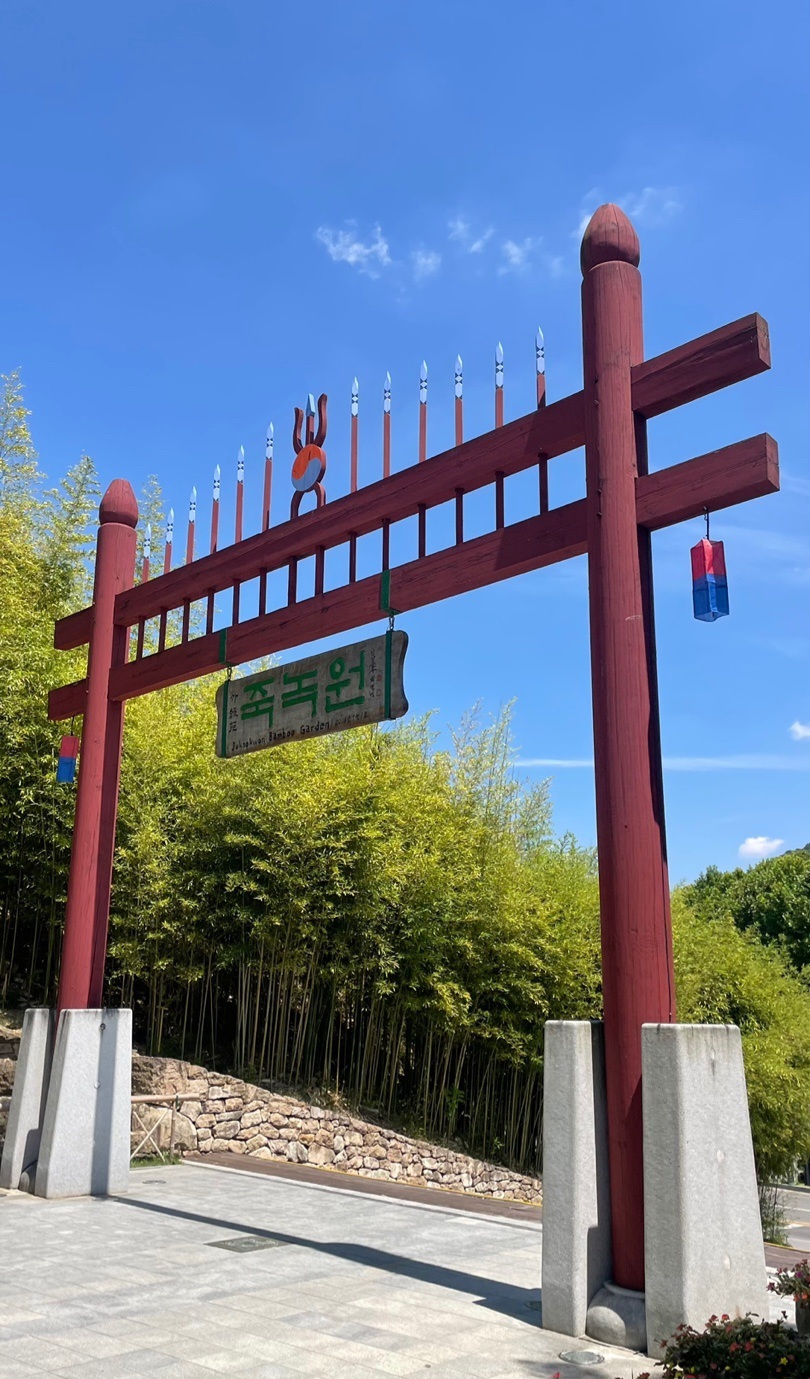 The red wooden entrance gate to Juknokwon bamboo garden in Damyang, with bamboo growing behind it