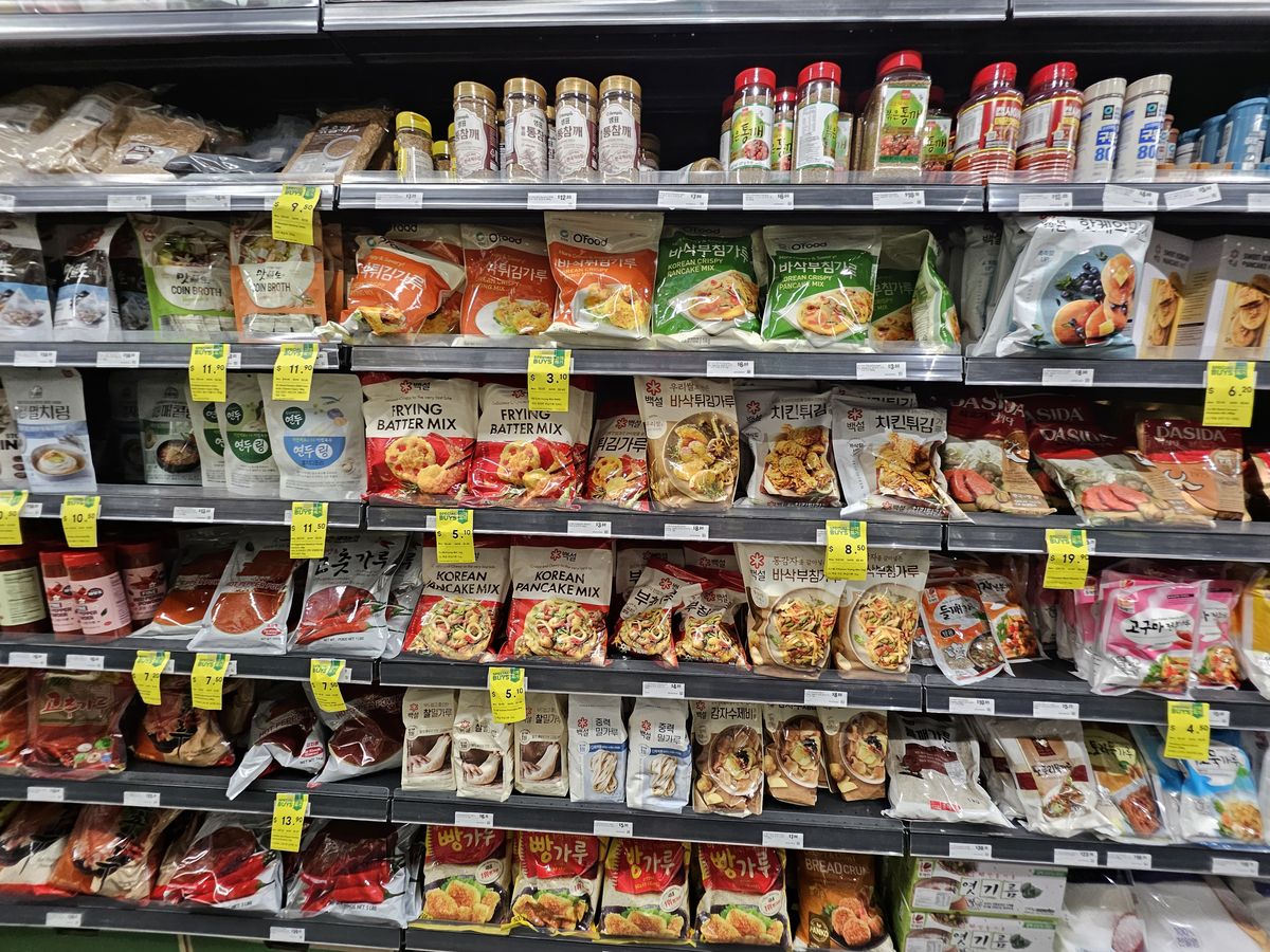 Supermarket shelves of Korean frying batter mix, pancake mix, chicken frying mix and breadcrumbs — bags of wheat-based coating flours.