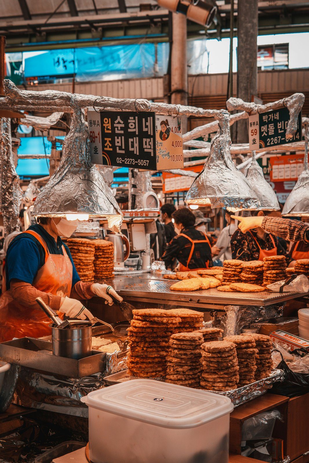 A vendor frying bindaetteok mung-bean pancakes at Gwangjang Market, Seoul