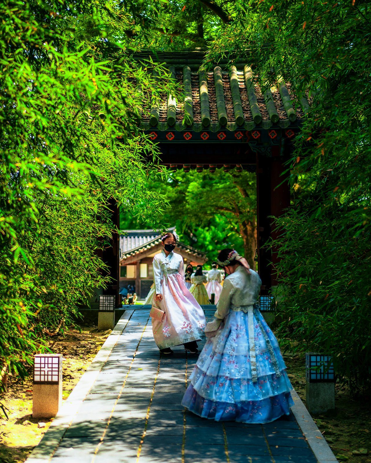 Two people in hanbok walking through a traditional gate