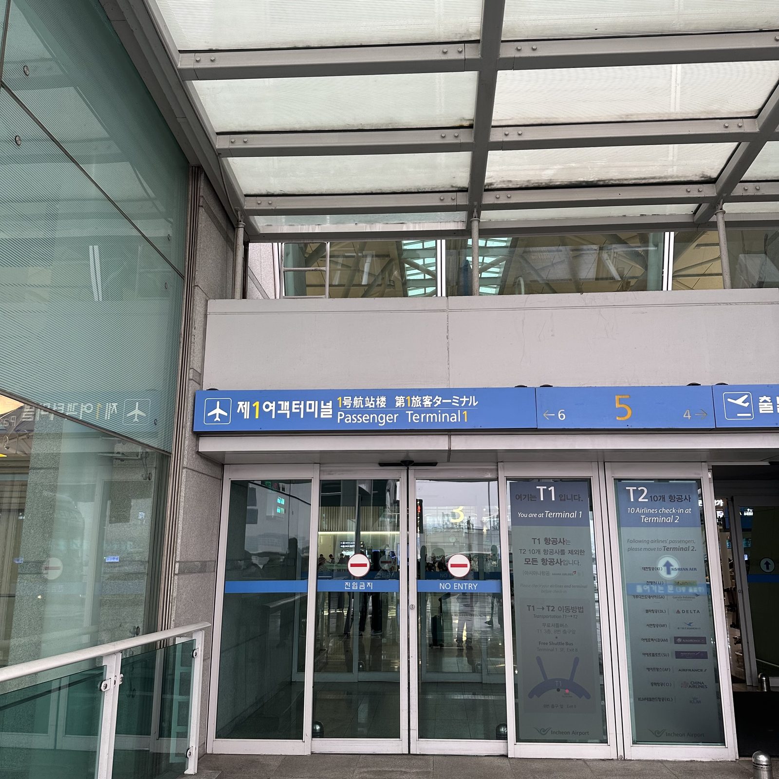 Entrance door 5 of Incheon Airport Terminal 1, with the Passenger Terminal 1 sign and separate T1 and T2 markings on the doors