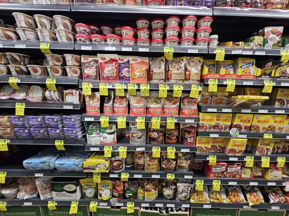 Shelves of Korean instant meals: rice porridge (juk) bowls, microwave rice, instant curry and soup pouches.