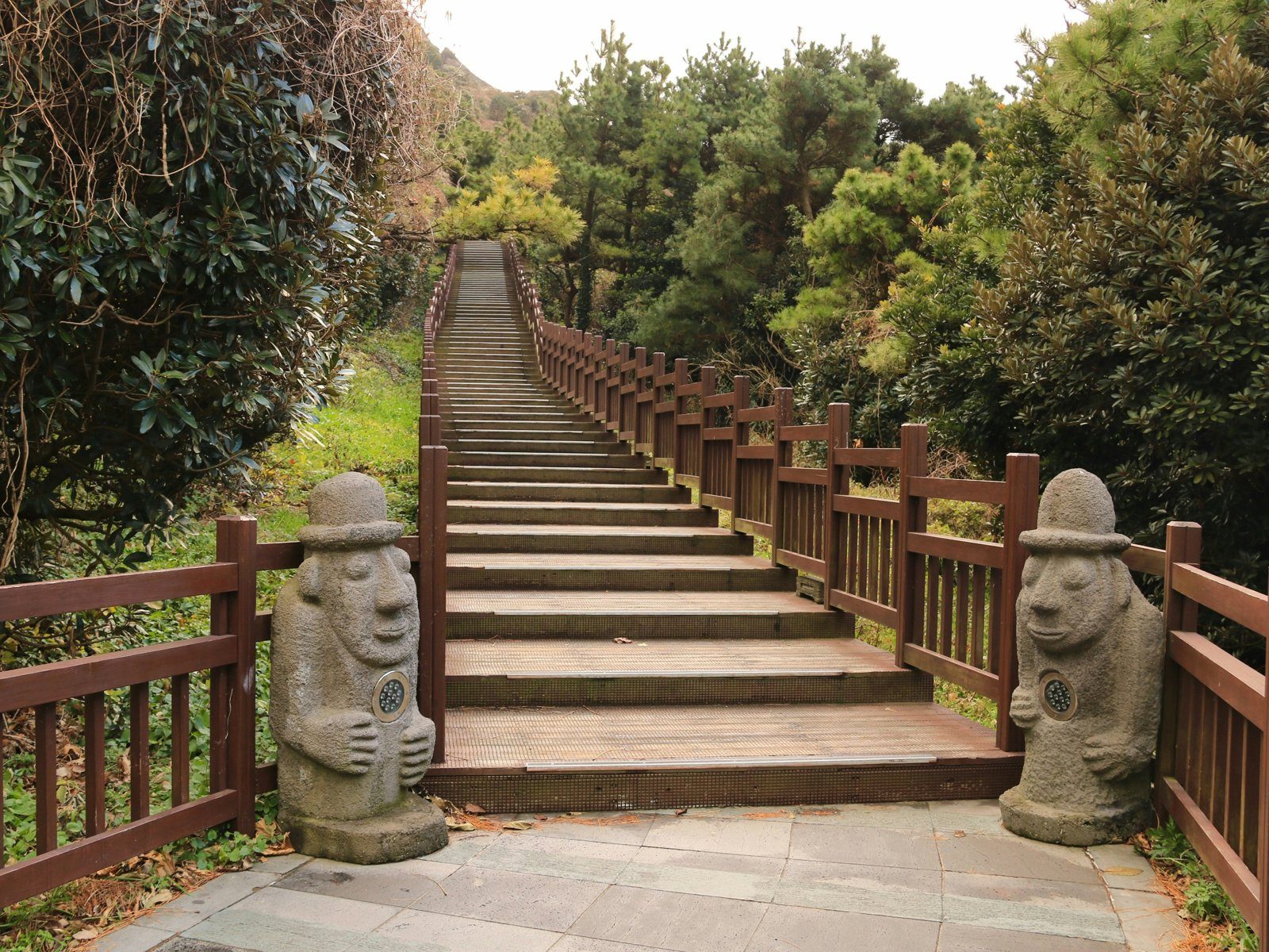 Jeju dol hareubang stone grandfather statues beside a stairway on Jeju Island