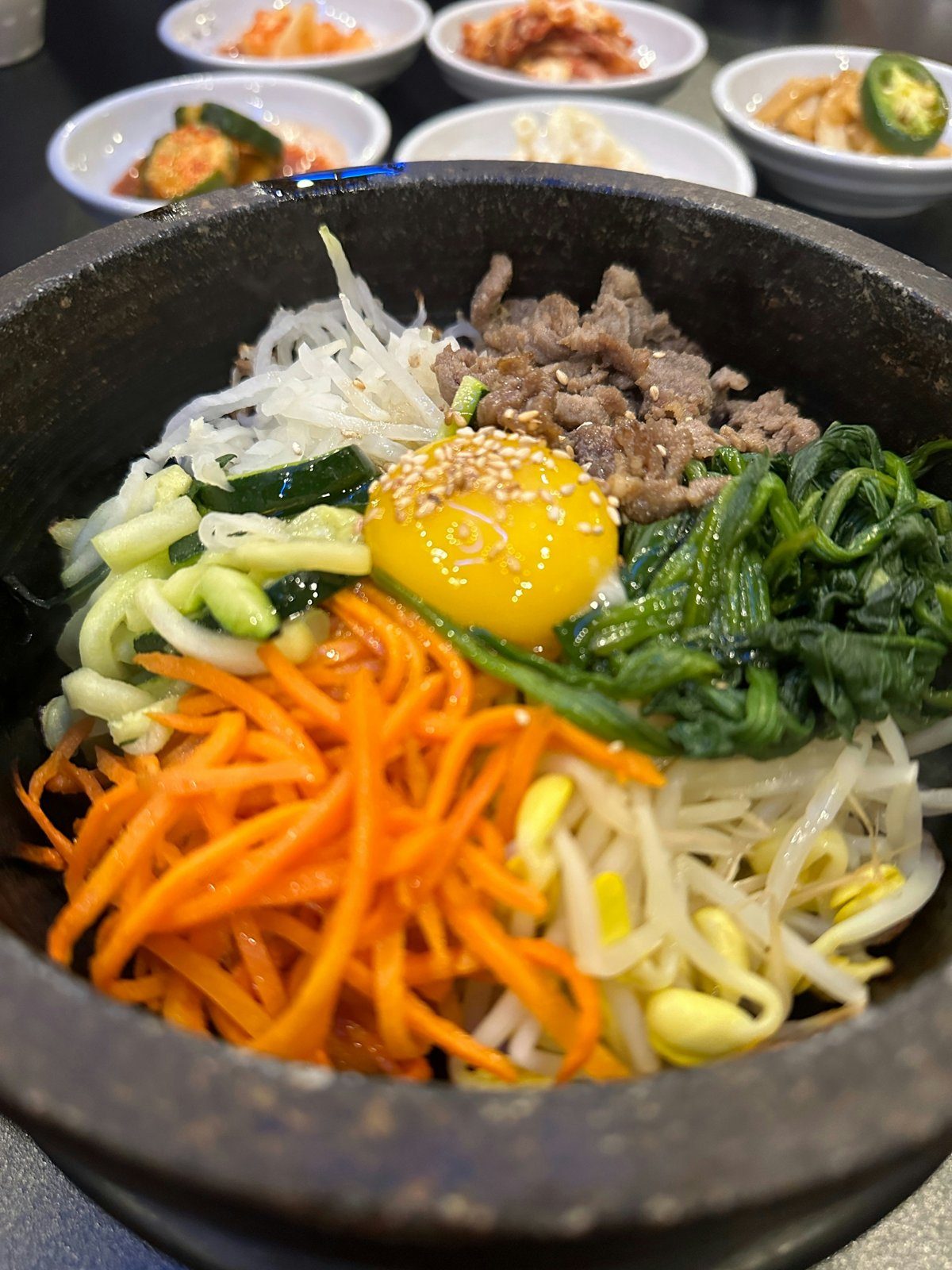 Dolsot bibimbap — Korean mixed rice in a hot stone bowl with a raw egg