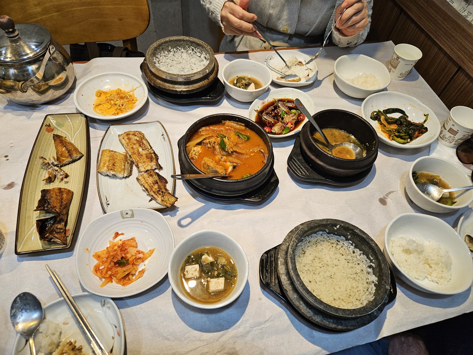 A Korean hanjeongsik set with grilled fish, stews in stone pots, rice and many side dishes