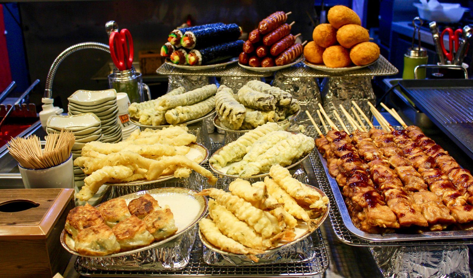 A Korean market street-food stall piled with eomuk, twigim, gimbap and skewers