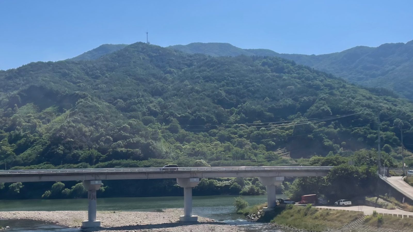 The Seomjin River in Hadong seen from above — pale blue water, gravel bars and a road bridge below the green foothills of Jirisan