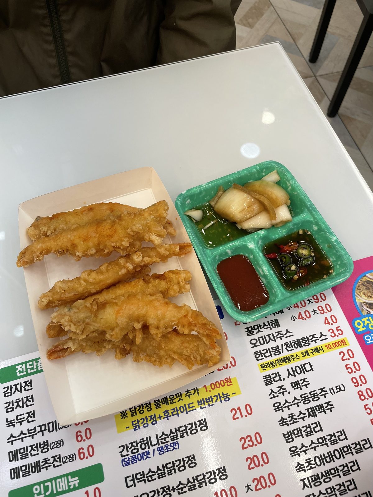 A tray of freshly fried shrimp tempura with pickled radish and dipping sauces at Sokcho's central market