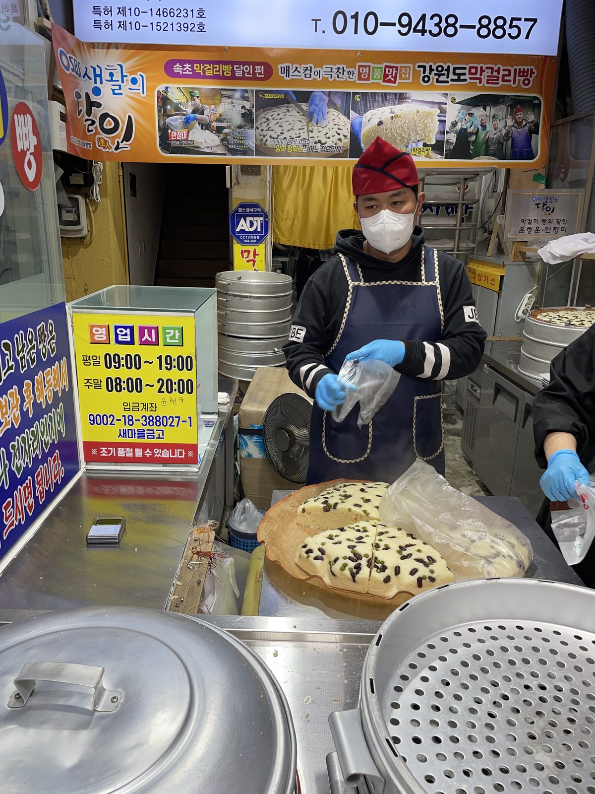 A vendor bagging Gangwon-do makgeolli bread at a stall in Sokcho's central market